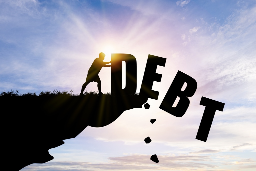 Man pushing debt down cliffside, learning how to get out of a personal loan debt