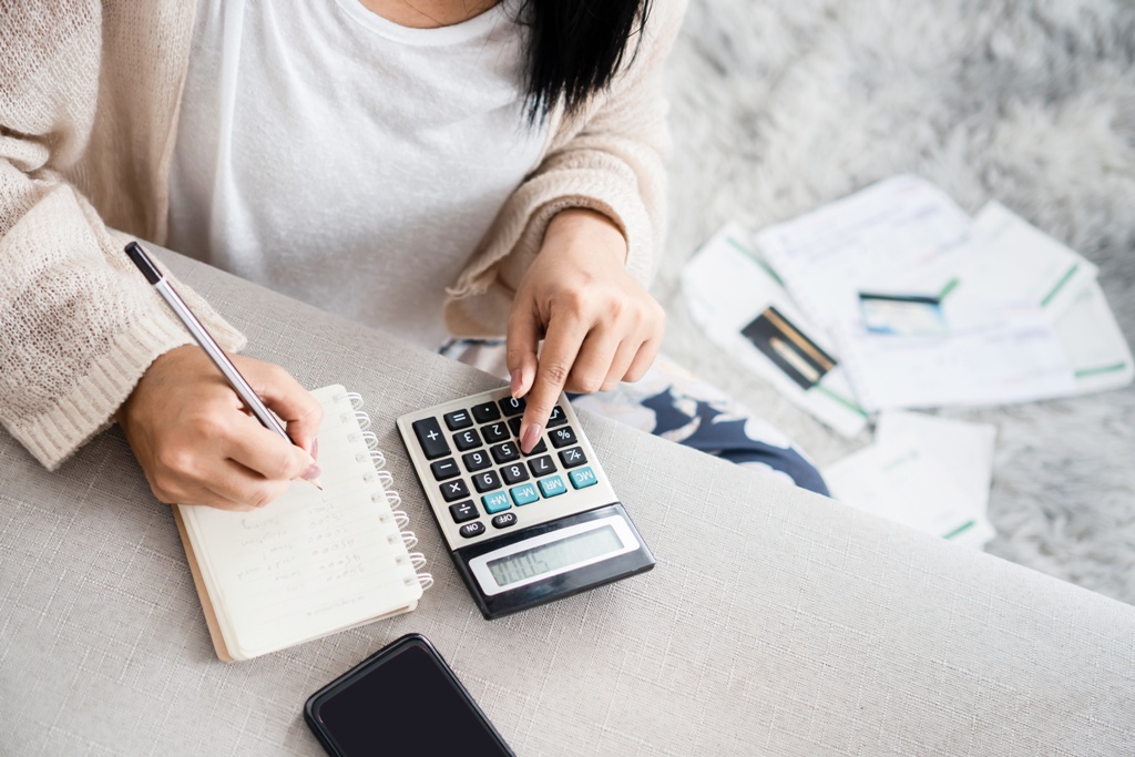 Woman calculating and jotting down steps to pay off multiple payday loans using debt consolidation loan