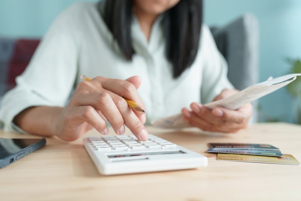 Closeup of a woman calculating bills and debts, considering getting a 1-month loan