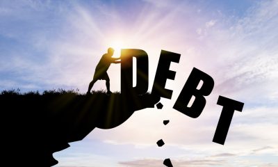 Man pushing debt down cliffside, learning how to get out of a personal loan debt